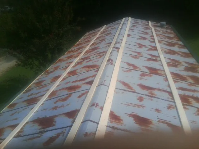 Rusted metal roof panels with new wood purlins before replacement — Storm Damage Roof Repair in North Brookfield by Roofing Brothers