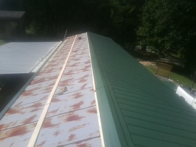 Old rusted panels beside newly installed green metal roofing — Wind Damage Roof Repair by Roofing Brothers in North Brookfield