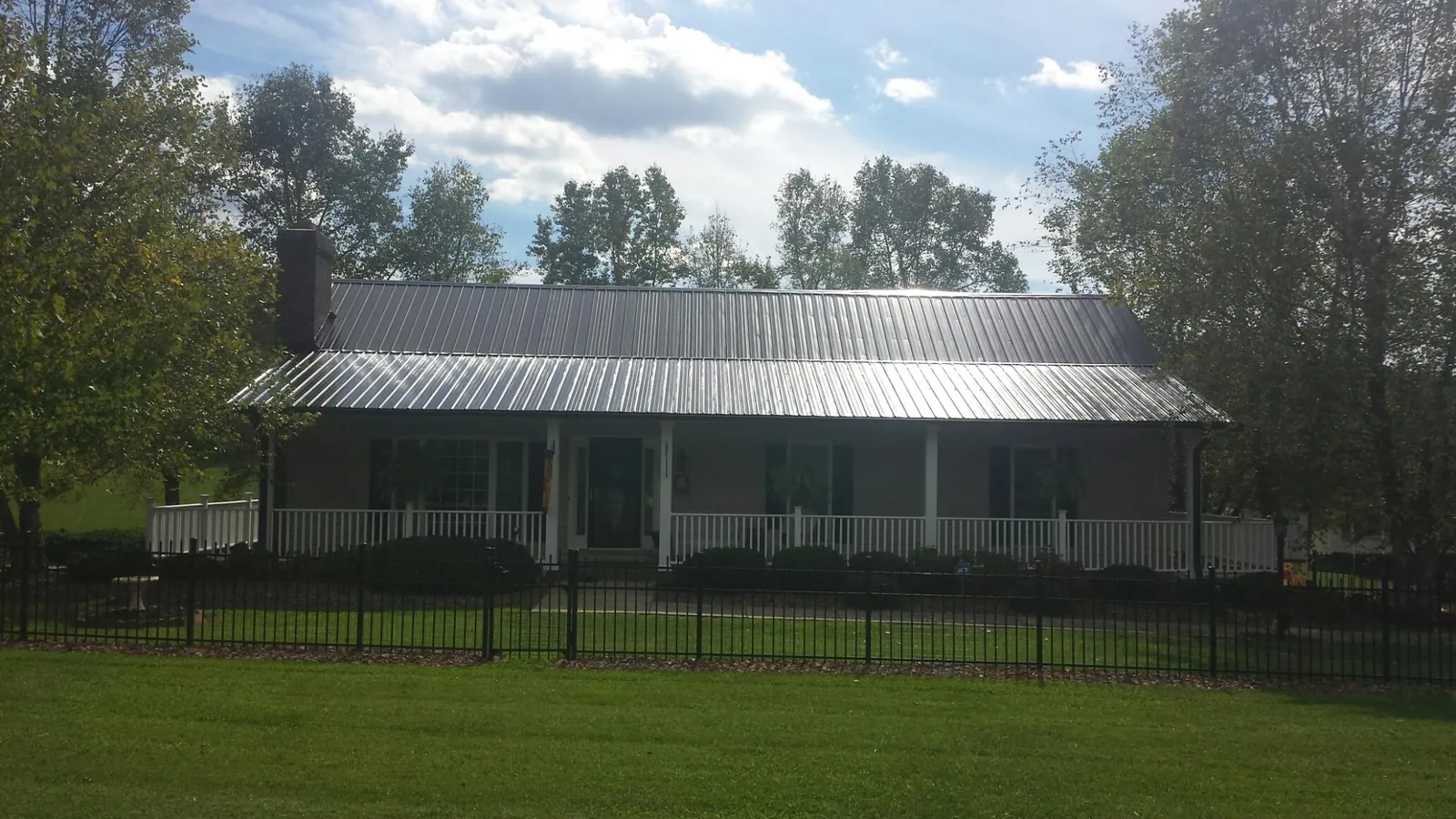 Gray metal roof on a brick ranch with a full width front porch — Gutter Guard Installation work by our crew in North Brookfield